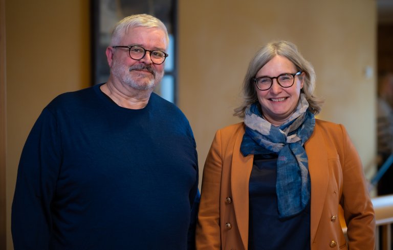 Foto av de to IA-rådgiverne Åmund Austdal og Else-Marit Steinstad Bakke. Åmund står til venstre i bildet i mørk blå genser. Han har grått hår og skjegg. Else-Marit står til høyre med en oransje blazer, mørk genser og et blått og grått skjerf.