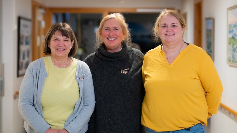 Bilde av tre damer, ståande saman i ein korridor på Smøla sjukeheim; avdelingsleiar Synøve Jota Gulla, einingsleiar Inger-Lise Lervik og verneombod Unni Betten. Foto.