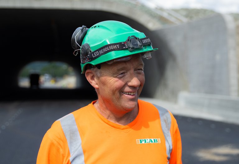 Egil Fredriksen står med arbeidshjelm og arbeidsuniform utenfor en tunnell.jpg